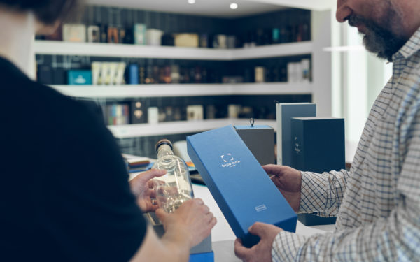 Two people in a retail outlet looking at rigid packaging for luxury drinks